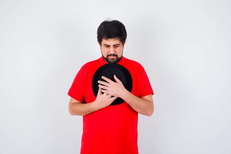 Dark Haired Man Red T Shirt Hugging His Cap Looking Hopeful Front View 176474 84784